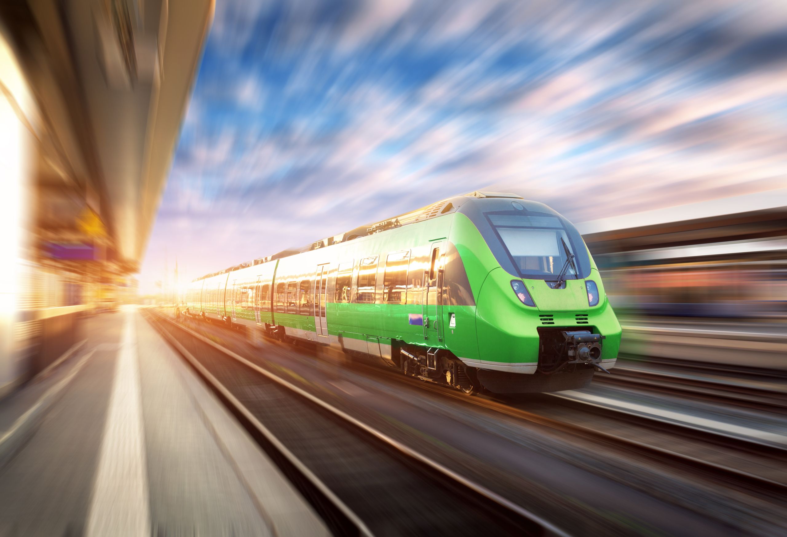 Image of a Speedy Green Train going though a railway station with a motion blur background